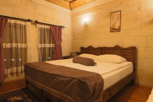 于尔居普Aja Cappadocia Cave Hotel的一间卧室配有一张带白色床单的大床