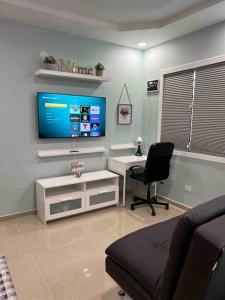 乌马考Palmas View Premium 6的客厅配有电视、椅子和书桌