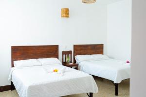 弗洛勒斯Casa Ramona的两张床,配有白色床单和一朵花