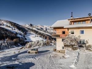 圣卡夏诺Garni Baita的停在雪地的建筑物前面的汽车