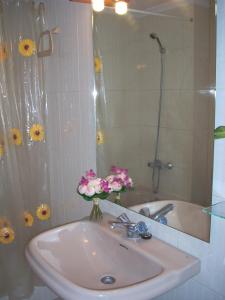 贝纳斯克Apartamentos Los Tilos的浴室设有水槽、镜子和鲜花