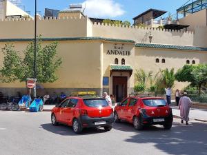 非斯安达利比住宿酒店的两辆红色汽车停在大楼前