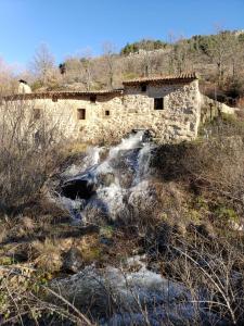 拿瓦费彼迪亚-德科尔Las Tejeruelas Casa Rural的田野里河边的石头建筑