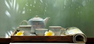 库斯哈尔纳加尔库格阿曼瓦纳spa度假村的盘子,盘子上装有杯子,茶壶和鲜花