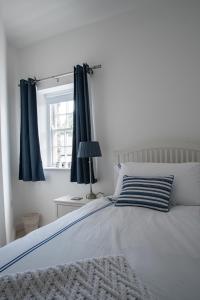 DundrumHeritage Cottages Dundrum的一间卧室配有一张带蓝色窗帘的床和一扇窗户