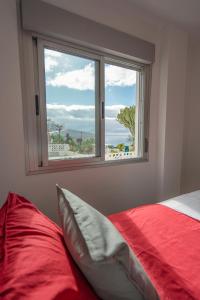塔瓦伊瓦Luxurious apartment with large terrace and sea views的一间卧室设有红色的床和窗户。