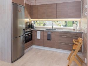 NiskalaHoliday Home Holy lake rantasauna by Interhome的厨房配有木制橱柜和不锈钢冰箱。