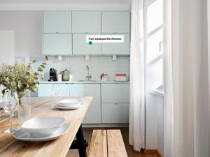 萨尔茨堡numa I Flute Apartments的厨房配有木桌和白色橱柜。