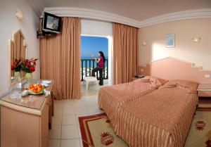 苏塞皇家海滩酒店的一间酒店客房,配有一张床和一个女士,从窗户望出去