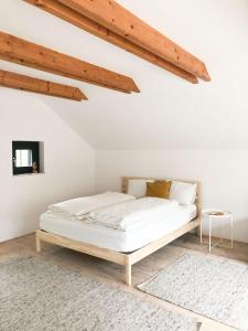 林茨ENTZÜCKENDES GÄSTESTÖCKL am Linzer Pöstlingberg的白色客房的一张床位,设有木制天花板