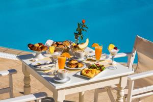乔拉弗雷恩多斯Hotel Odysseus的一张桌子,上面放着早餐食品和橙汁
