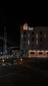 艾卜哈Beautat Hotel的夜间的酒店大楼,上面有标志