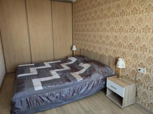 哈普萨卢Apartment Südalinnas的一间卧室配有一张床和一张带台灯的桌子