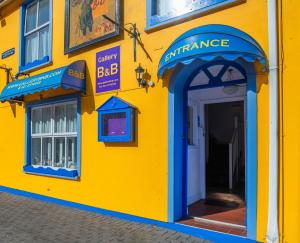 金塞尔The Gallery B&B, the Glen, Kinsale ,County Cork的黄色建筑,入口处有蓝色门廊