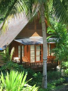 沙拉海滩Green Papaya Beach Resort, Koh Phangan的一座带门廊和棕榈树的木屋