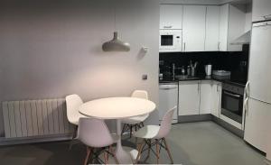 伊瓜拉达Apartamento con encanto的白色的厨房配有白色的桌子和椅子