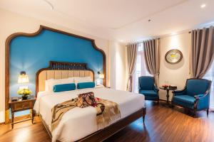 河内河内特兰特酒店的一间卧室配有一张大床和两张蓝色椅子