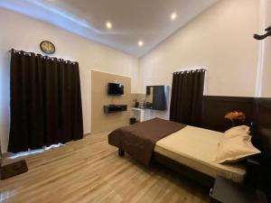 科代卡纳尔RR Holidays - Home Stay的一间卧室配有一张带黑色窗帘的床和电视。