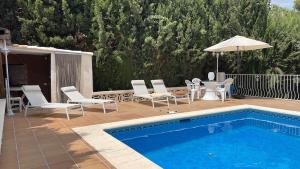 贝尼多姆Villa Mis 5 Amores con piscina的游泳池旁配有椅子和遮阳伞