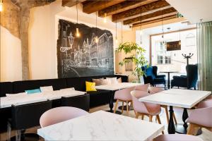 塔林美利通旧城伽登酒店的用餐室配有桌椅,墙上挂有绘画作品