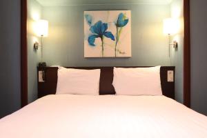 巴黎蒙帕纳斯提姆敖德萨酒店的卧室配有一张带两个灯的大白色床
