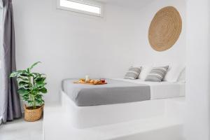 纳克索乔拉Krina Mare Boutique Hotel的一间白色卧室,配有床和植物