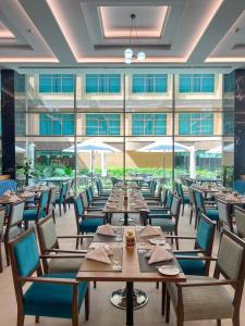 巴士拉Grand Millennium Al Seef Basra的餐厅设有桌椅和大窗户。