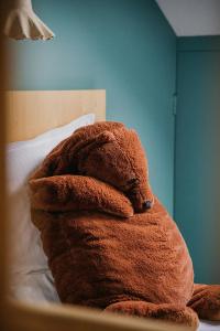 巴斯洛内特Hotel Spa Azteca Barcelonnette的棕色泰迪熊坐在床上