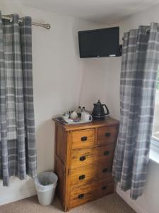 KinnersleyROYAL OAK的卧室配有木制梳妆台,墙上配有电视