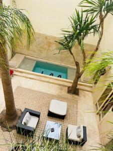 马拉喀什144号摩洛哥传统庭院旅馆的一个带两把椅子和一张桌子的游泳池以及两棵棕榈树