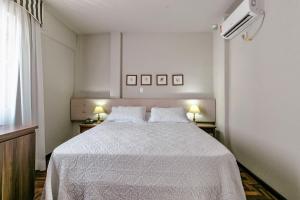 Pôrto UniãoHotel San Rafael的一间卧室配有一张带白色床单和两盏灯的床。