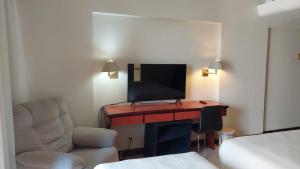 巴西利亚Flat Particular Hotel Kubitschek的客房设有书桌、电视和椅子