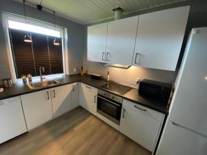 布罗艾厄AgerBro的厨房配有白色橱柜、水槽和冰箱。