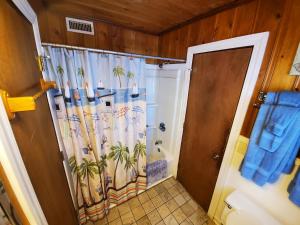 默特尔比奇Atlantic Winds Condos的浴室设有淋浴和棕榈树遮帘。