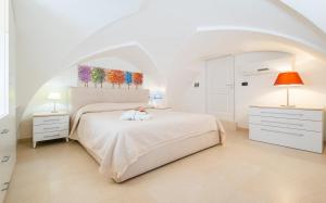 莱乌卡Le Pativite Luxury Apartments by HDSalento的白色卧室配有白色的床和两盏灯。