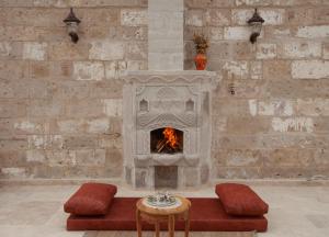 于尔居普Narcissos Cave Hotel的配有桌椅的客房内的石头壁炉