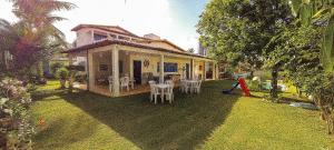 帕纳米林Qavi - Casa com piscina na Praia de Cotovelo的房屋设有庭院、椅子和桌子