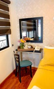 昆卡HOSTAL EL CAJAS的一间卧室配有一张桌子、一把椅子和一面镜子