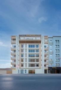 马斯喀特Centara Life Muscat Dunes Hotel的一座大型白色公寓大楼,设有停车场