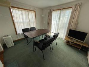 北斗市HOKUTO SATOYAMA BASE的客厅配有桌椅和电视。