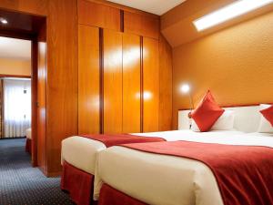 安道尔城安道尔美居酒店的酒店客房,设有两张床和木墙