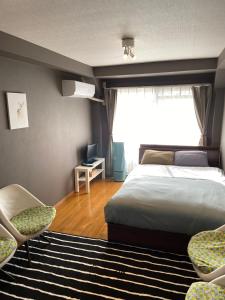 太宰府市SONIC APARTMENT HOTEL的一间卧室配有一张床、两把椅子和一个窗户