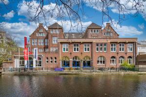 海牙Stayokay Hostel Den Haag的水体旁边的一个大砖砌建筑