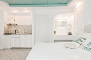 纳克索乔拉Naxos Evilion Luxury Apartments & Suites的白色卧室设有白色的床和厨房