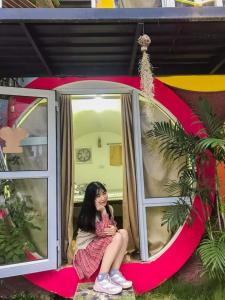 木州县MŨM HOMESTAY MỘC CHÂU的坐在房子窗户上的女孩
