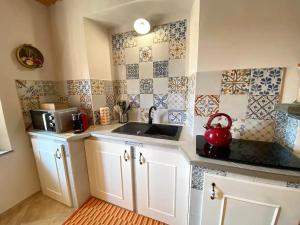 希尼奥Casa Vacanze Cascina Mombello的厨房配有白色橱柜、水槽和瓷砖