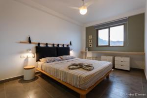 明德卢Seafront Holiday House on the Mindelo Bay的一间带一张大床的卧室,位于带窗户的房间内