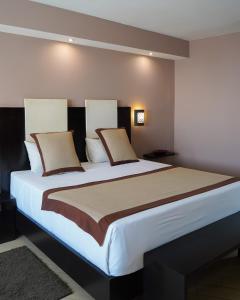 达喀尔罗马咖啡酒店的卧室配有一张带白色床单和枕头的大床。