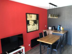 杜瓦讷内Très bel appartement vue mer avec piscine的一间拥有红色墙壁、一张桌子和电视的用餐室