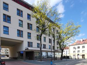 比亚韦斯托克Apartament SixtySix 66 z kominkiem的前面有一棵树的白色大建筑